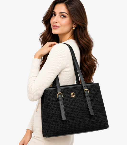 Tommy Hilfiger Women's Black Monogram Tote Bag with gold-tone logo, dual shoulder straps and structured design styled on a female model.