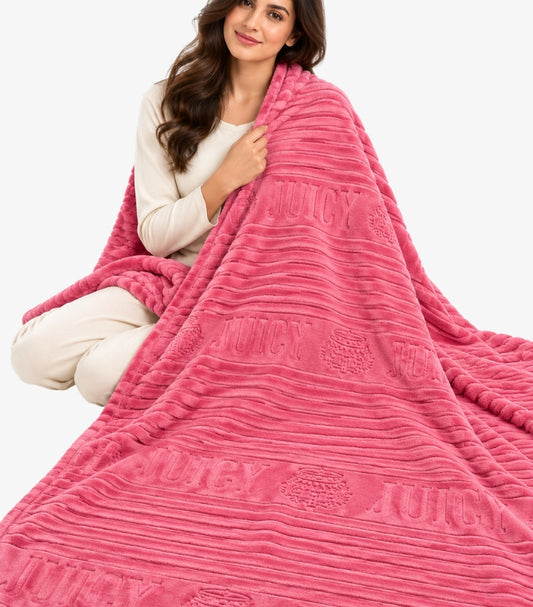 Woman wrapped in a pink Juicy Couture ribbed plush throw blanket with embossed logo and crest design