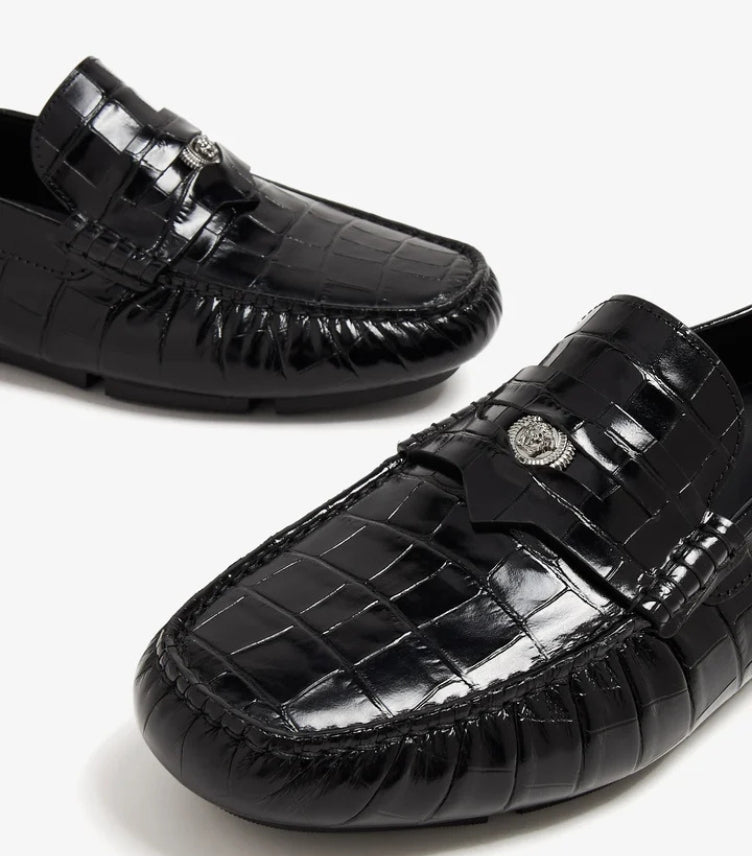 Close-up of Versace Medusa emblem on leather loafer