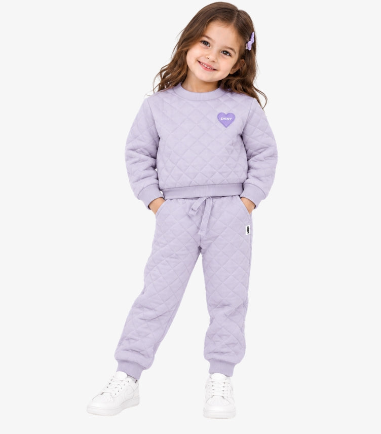 Girl wearing a DKNY lilac diamond-quilted tracksuit with a heart-logo sweatshirt and matching drawstring joggers