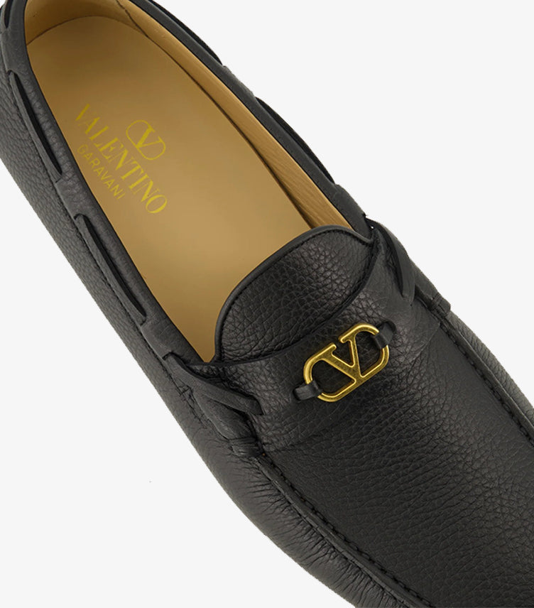 Valentino Garavani black leather loafer close-up showing gold-tone VLogo hardware and textured leather
