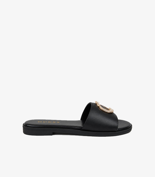 GUESS Los Angeles black leather flat slide sandal side profile showing wide strap crystal medallion and flat black sole