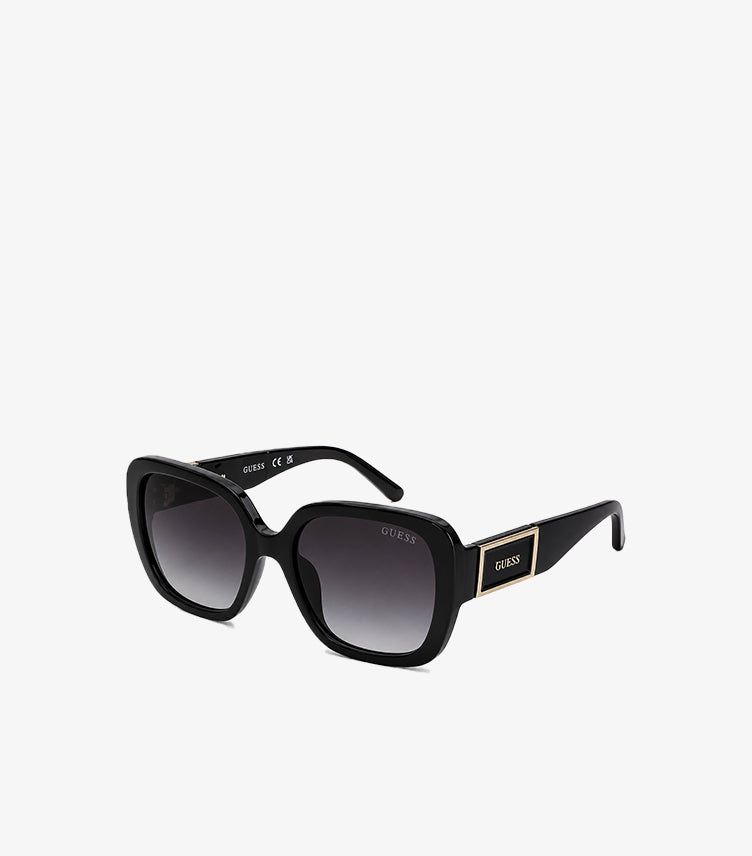 Front view of Guess women’s black oversized square sunglasses with dark gradient lenses and gold logo plaques