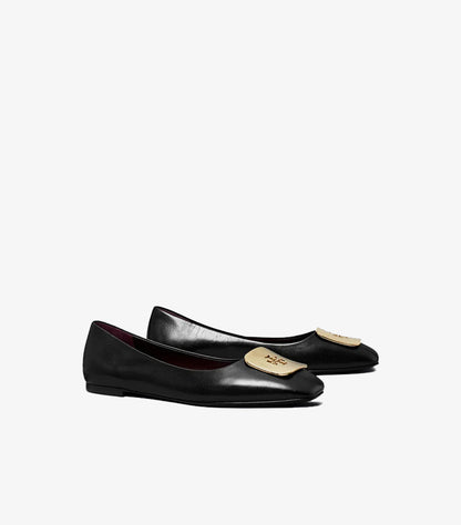 Angled view of Tory Burch black ballet flats featuring gold-tone logo plaques and low-profile soles