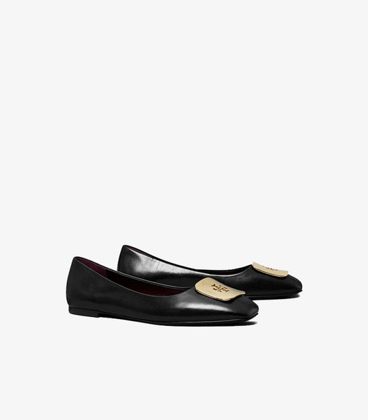 Angled view of Tory Burch black ballet flats featuring gold-tone logo plaques and low-profile soles