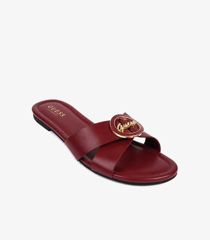 GUESS burgundy leather cross-strap flat slide sandals angled view showing gold GUESS script logo medallion and branded insole