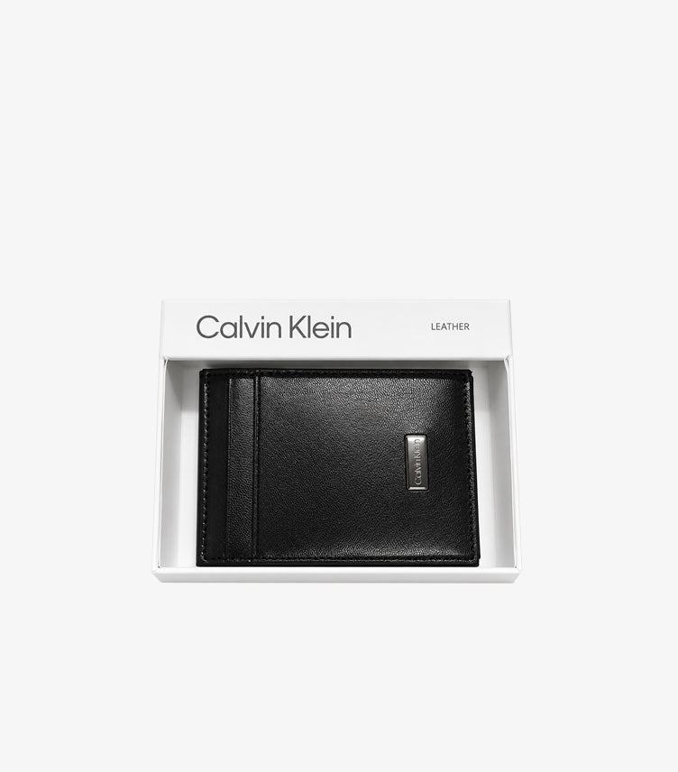 Calvin Klein black leather bifold card holder with metal logo plaque displayed in branded gift box