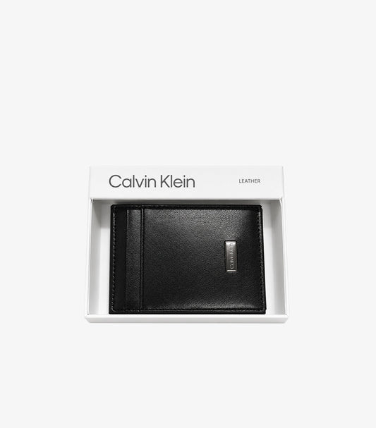 Calvin Klein black leather bifold card holder with metal logo plaque displayed in branded gift box