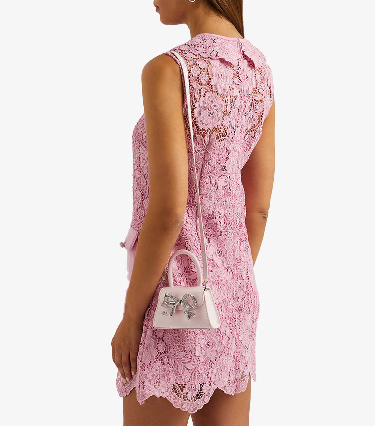 Model wearing Self-Portrait pink crystal bow mini bag as crossbody with detachable strap and pink lace dress