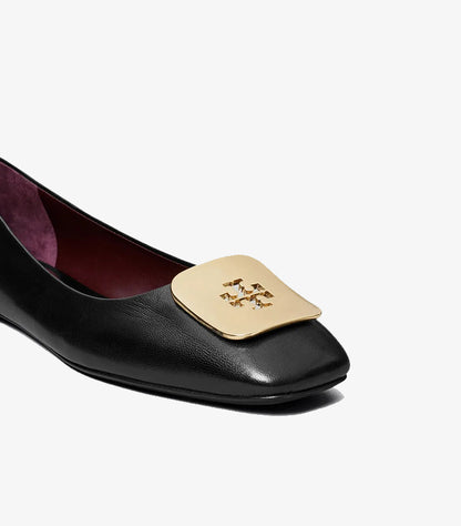 Close-up of Tory Burch ballet flat showing smooth black finish and gold Double T cut-out plaque