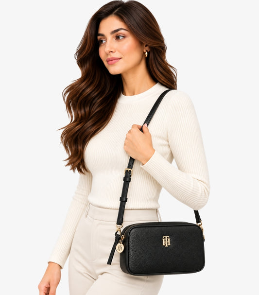 Tommy Hilfiger Women's Black Crossbody Camera Bag with gold-tone logo and adjustable shoulder strap styled on a female model.