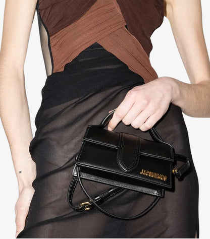 Model holding Jacquemus Le Bambino Long black top-handle bag