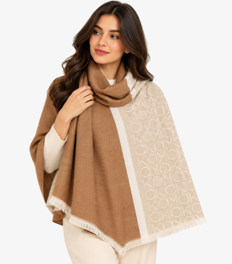 Woman wearing a Calvin Klein brown and beige two-tone monogram shawl with contrasting border and fringed edges