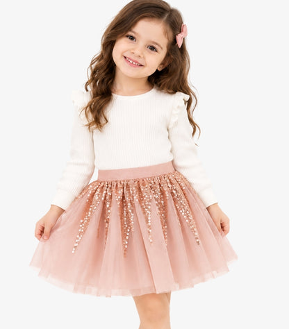 Girl wearing a Primark blush pink sequin tulle party skirt styled with a white long-sleeve ruffle top