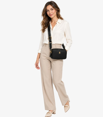 Woman wearing a Tommy Hilfiger double-zip camera bag with a wide branded adjustable crossbody strap