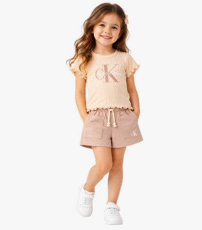 Calvin Klein Jeans girls' beige ribbed T-shirt and shorts set featuring CK logo, ruffle sleeves and drawstring shorts worn by a young girl.