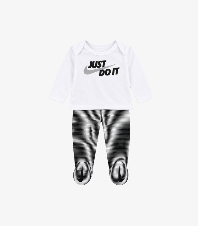 Nike baby two-piece outfit featuring white Just Do It long sleeve top with Swoosh logo and black and white striped footed pants.