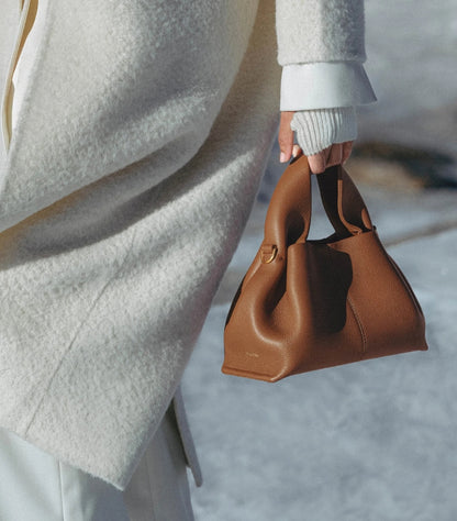 Close-Up Detail of Polène Numéro Nine Mini Tan Caramel Grained Leather Bag with Embossed Logo and Gold D-Ring Hardware – Held by Model in White Coat