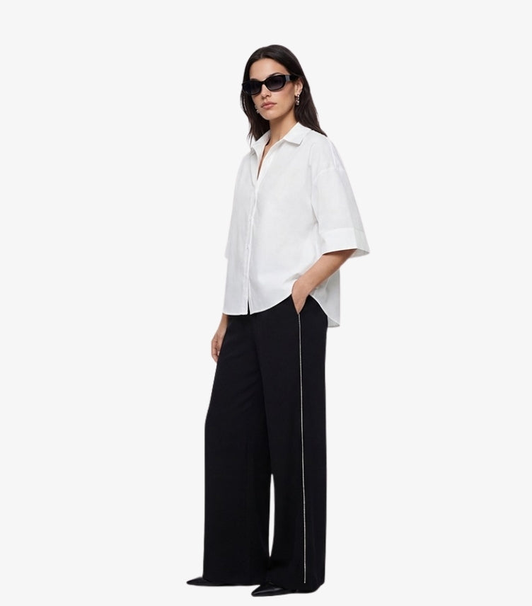 M&S women's black wide-leg trousers with white contrast side stripe on model styled with white cotton shirt and black sunglasses