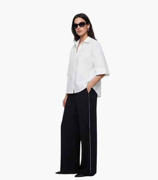 M&S women's black wide-leg trousers with white contrast side stripe on model styled with white cotton shirt and black sunglasses