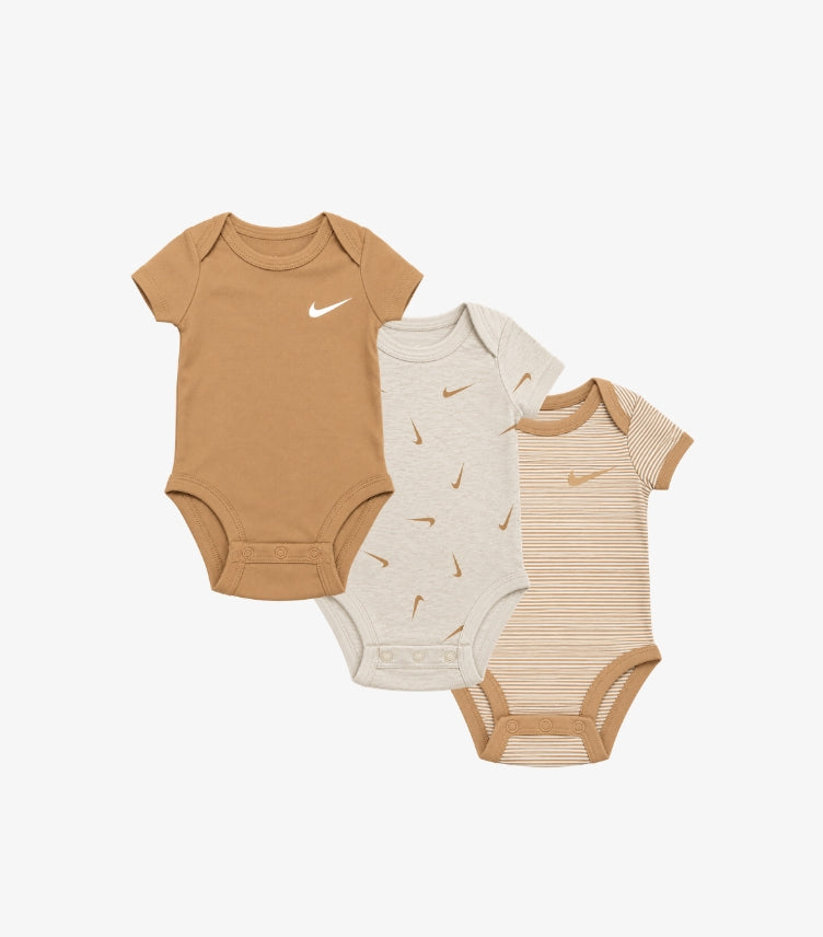 Nike baby boys 3-pack short sleeve bodysuits featuring solid Swoosh logo, all-over Nike print and striped design with envelope necklines and snap closures.