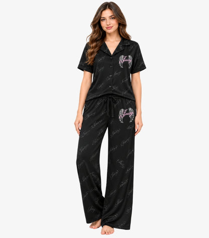 Juicy Couture Women's Black Juicy Angel Pajama Set featuring a button-down short-sleeve shirt, pink angel wing logo, drawstring waist and matching wide-leg trousers.