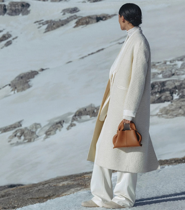Polène Paris Numéro Nine Mini Tan Grained Leather Bag Carried by Model in White Wool Bouclé Coat and Wide Leg Trousers Against Alpine Snow Landscape – Quiet Luxury Editorial
