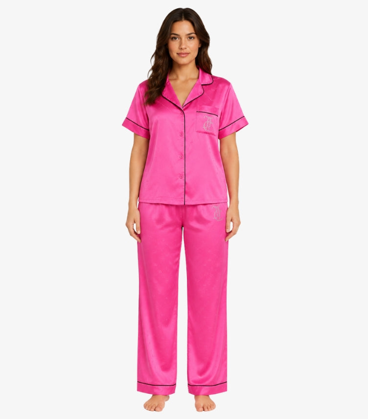 Juicy Couture women's pink satin pajama set with short sleeve button-up shirt, matching full-length pants, rhinestone logo, and contrast piping front view.