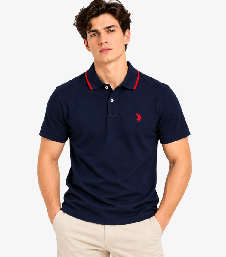Man wearing a U.S. Polo Assn. navy short-sleeve polo shirt with red collar trim and embroidered chest logo