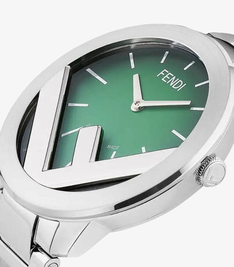Close-up of Fendi green gradient watch dial showing silver baton markers, two hands and polished FF design