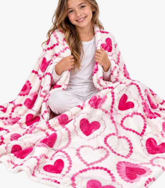 Juicy Couture white plush throw blanket with an all-over pink heart print styled around a model