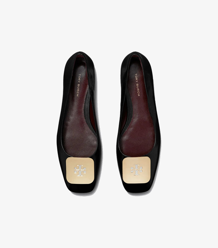 Top view of Tory Burch black square-toe ballet flats with gold logo plaques and burgundy interiors
