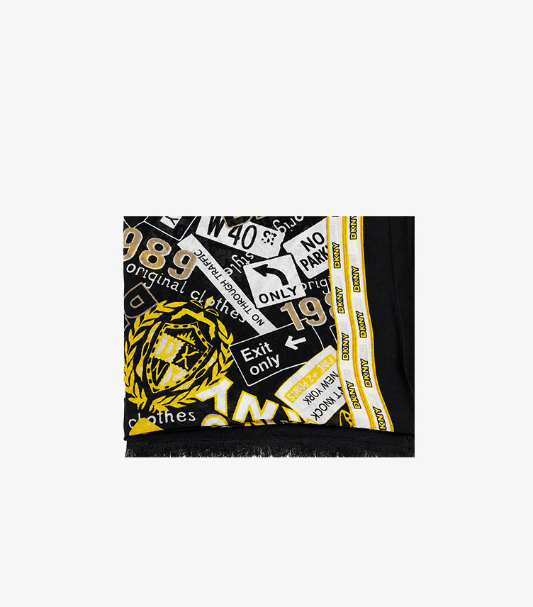 Close-up of DKNY women’s black graphic-print scarf with white and yellow New York motifs, logo border and fringed edge