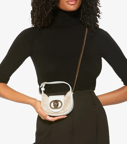 Woman carrying Kurt Geiger Micro Chelsea beige rattan crossbody bag with antique brass chain