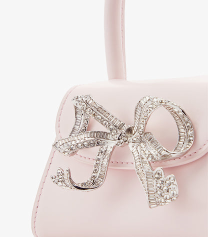 Close-up of Self-Portrait oversized baguette crystal bow embellishment on pink mini bag