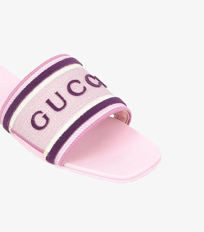Close-up of Gucci women’s pink slide sandal with embroidered purple logo and striped woven strap