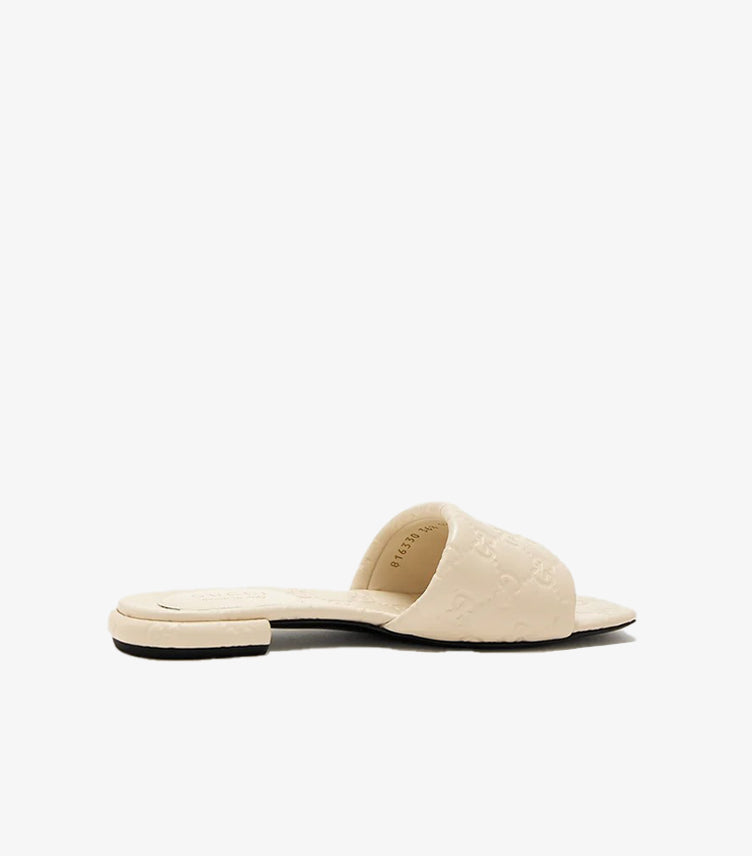 Gucci GG Matelassé cream quilted leather flat slide sandal left side view showing GG embossed strap and black outsole