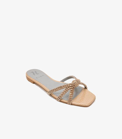 Angled view of GINA women’s champagne gold flat sandal with crystal crossover straps and square toe