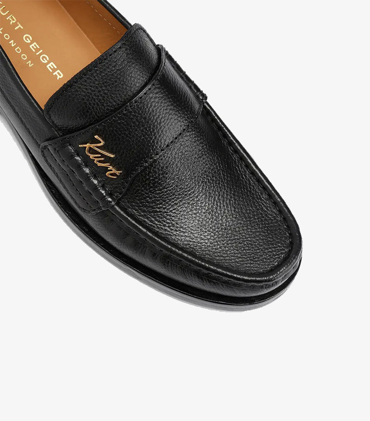Close-up of Kurt Geiger black pebbled leather penny loafer showcasing textured leather and gold signature logo.