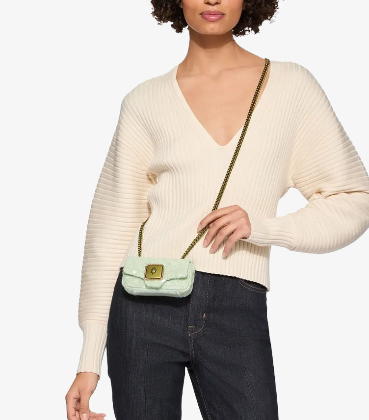 Model wearing Kurt Geiger mint-green sequin Micro Kensington crossbody bag with antiqued brass chain