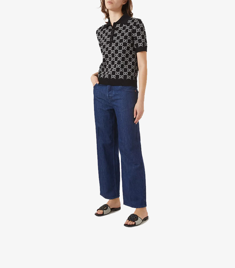 Model wearing Gucci Interlocking G flat slides with GG monogram polo and wide-leg blue jeans