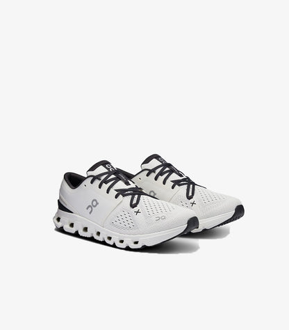 Angled view of On Running Cloud X white and black training shoes with mesh uppers and cloud-element soles