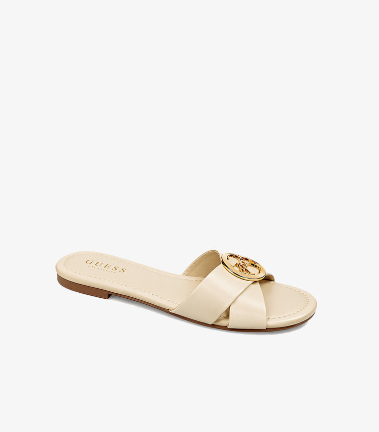 Angled view of Guess women’s cream open-toe slide featuring crossover straps and a gold-tone medallion