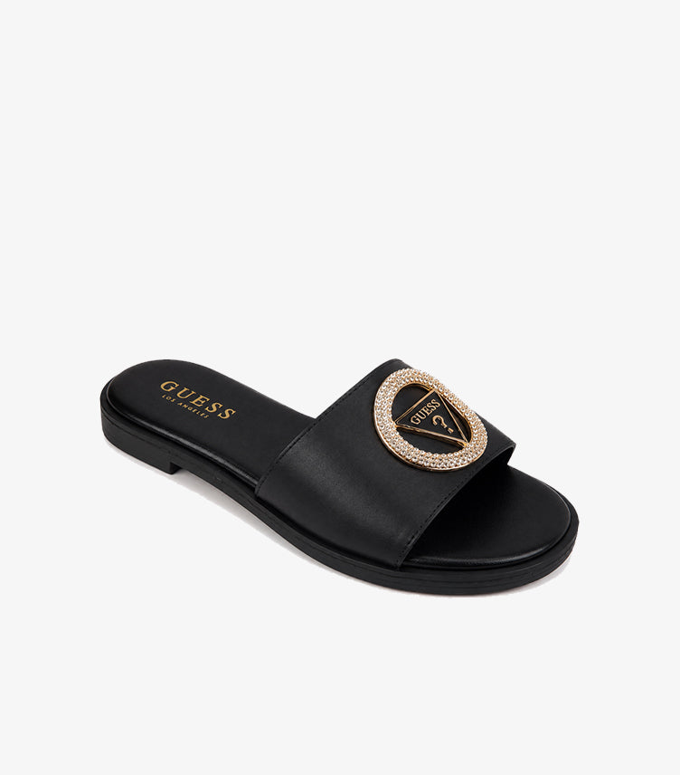 GUESS Los Angeles black smooth leather wide-strap flat slide sandal angled view showing crystal pave triangle logo gold medallion