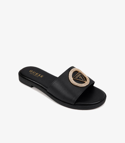 GUESS Los Angeles black smooth leather wide-strap flat slide sandal angled view showing crystal pave triangle logo gold medallion