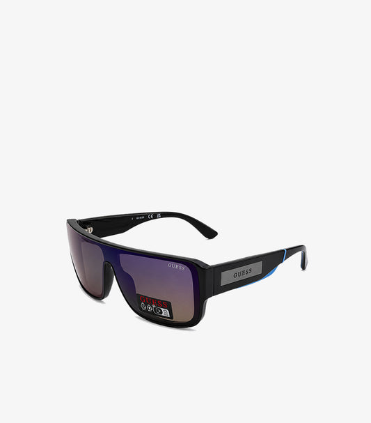 GUESS men's black shield visor flat-top sunglasses angled view showing purple blue gradient mirror lens grey GUESS badge temple and blue accent stripe