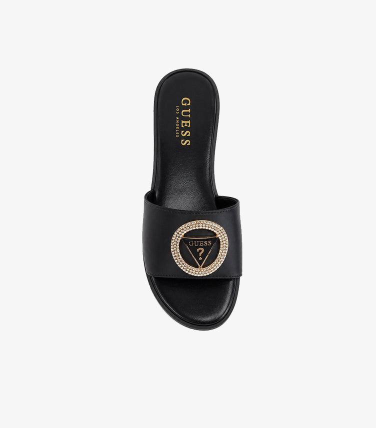 GUESS black wide-strap flat slides top-down view showing crystal pave GUESS triangle logo medallion and GUESS LOS ANGELES gold branded insole