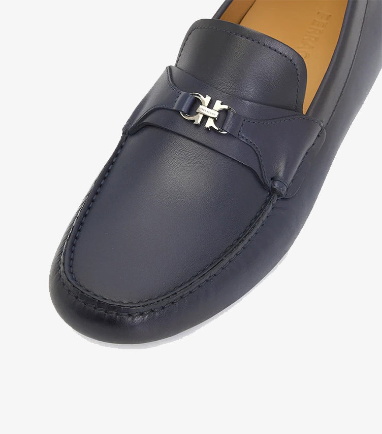 Close-up of Ferragamo navy leather loafer showing silver Gancini ornament and moccasin stitching