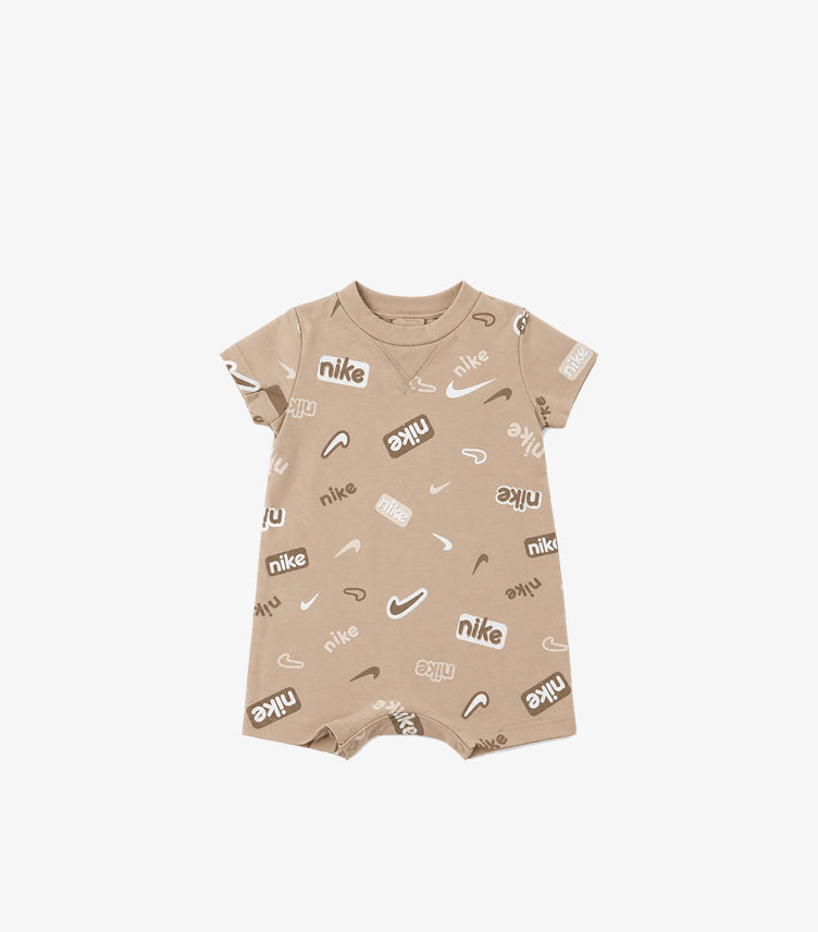 Front product view of Nike baby beige logo print romper with a round neck, short sleeves and short legs