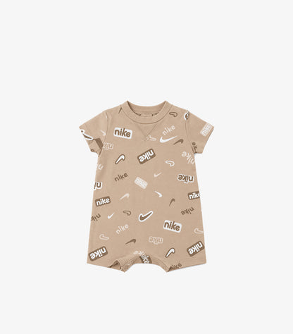 Front product view of Nike baby beige logo print romper with a round neck, short sleeves and short legs